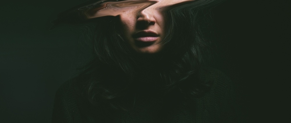 Woman against a black background with a blurred face